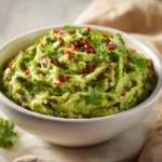 Fresh homemade Guacamole Recipe in white bowl with visible cilantro and onion