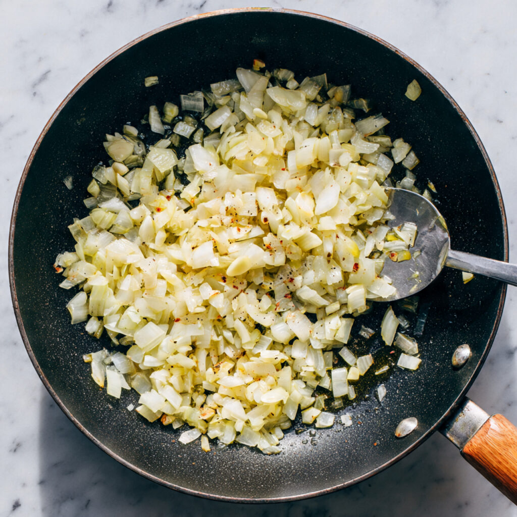 Creamy & Comforting Chicken Rice Casserole You’ll Make Again 3 close up of chopped onions and garlic cooking in a
